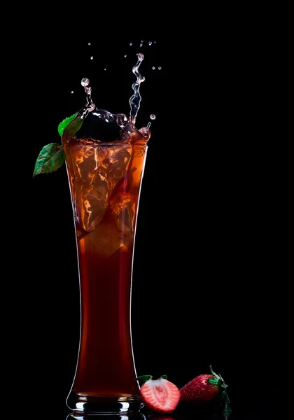Вид на клубничный сок, выплескивающийся из стекла на черную спину — стоковое фото