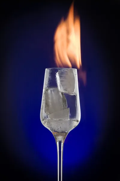 View of cocktail glass filled with burned ice on blue back — Stock Photo, Image