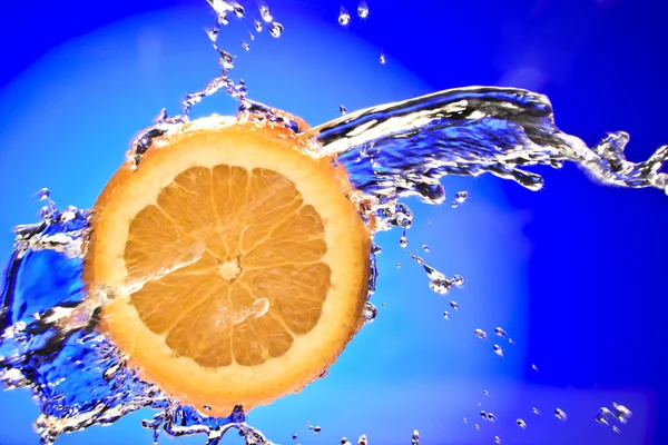 Close up view of sliced orange piece getting splashed with water — Stock Photo, Image