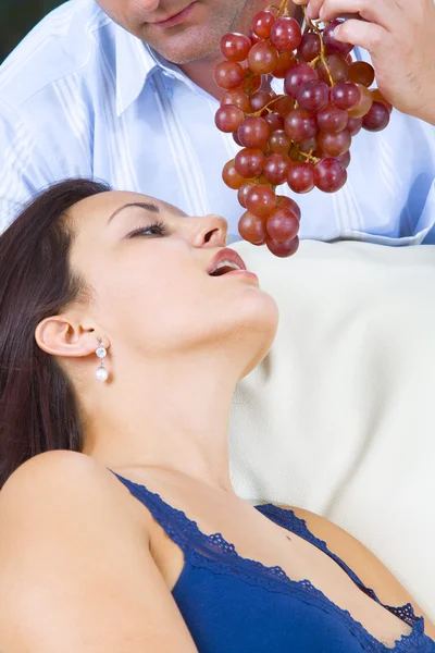 Close up portrait of nice young brunette getting tempted with grape — Stock Photo, Image