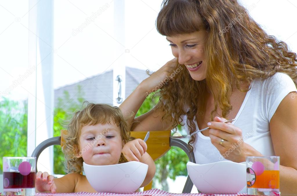 Portrait of young woman feeding her baby daughter