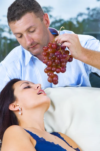 Close up portrait of nice young brunette getting tempted with grape — Stock Photo, Image