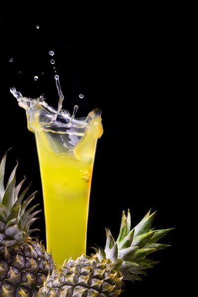 View of fresh pineapple juice splashing out of glass — Stock Photo, Image