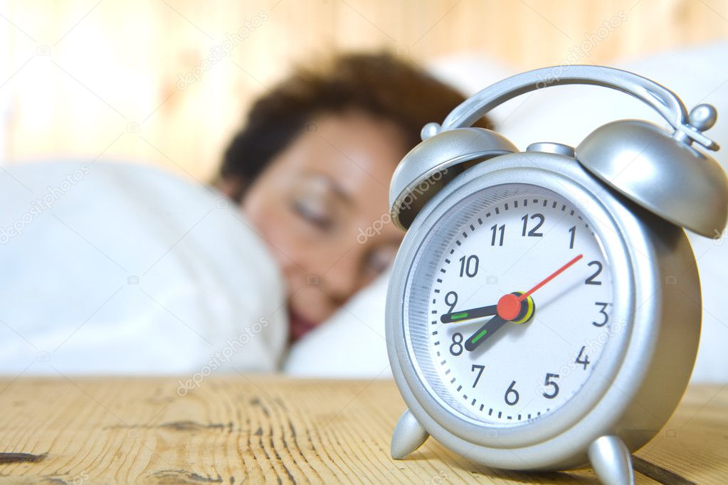Close up view of table clock and woman sleeping on back