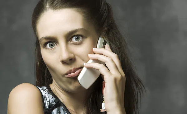 Retrato de mujer joven con teléfono móvil en espalda gris — Foto de Stock