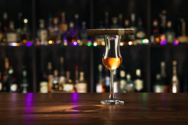 カラーバックの上にシガーを付けたラム酒のグラスを間近に見ることができます — ストック写真