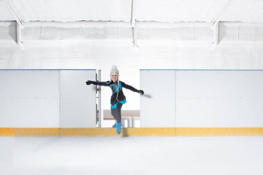 Mavi şapkalı küçük kız buz pateni yapmaya gidiyor.