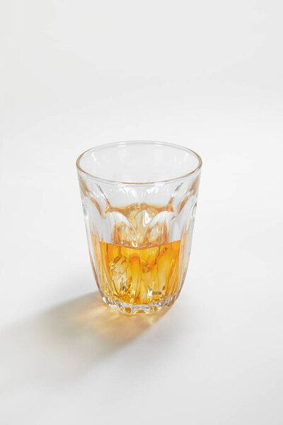 Close up view of glass of rum on white background