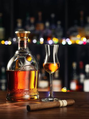 close up view of cigar, bottle of rum and glass aside on color back. 