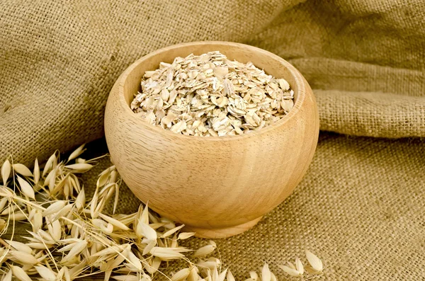 Oat flakes in a bowl on sacking — Stock Photo, Image