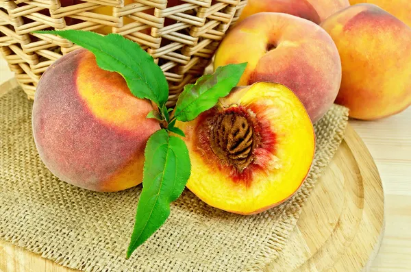 Peaches with leaves and a basket on board — Stock Photo, Image