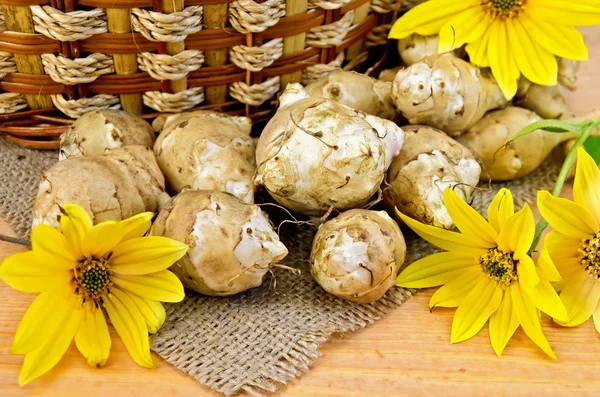 Jerusalem artichokes with yellow flowers and a basket — Stock Photo, Image