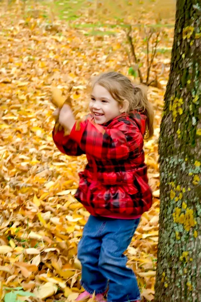 Liten flicka spelar med blad — Stockfoto