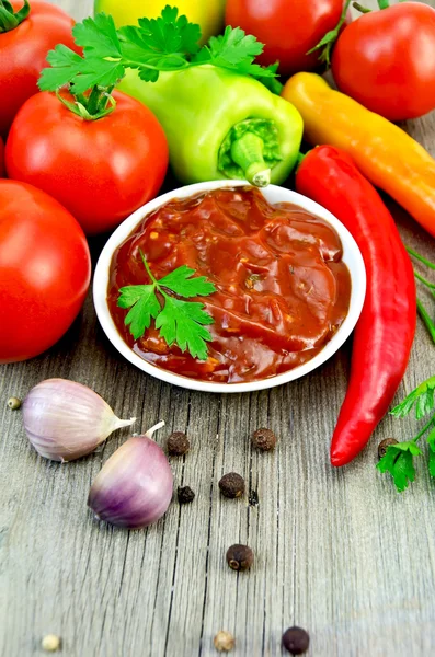 Ketchup with vegetables and spices on an old board — Stock Photo, Image