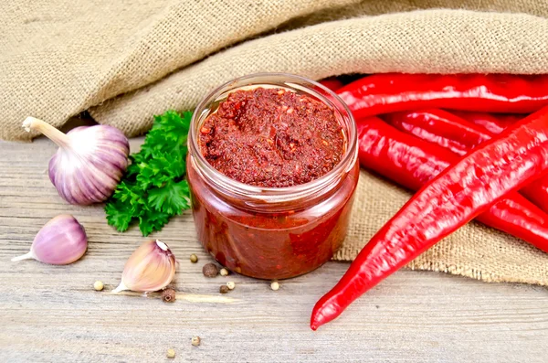 Ajika in a glass jar on sacking — Stock Photo, Image