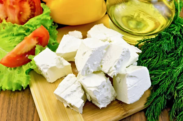 Feta cheese on the board with vegetables and oil — Stock Photo, Image