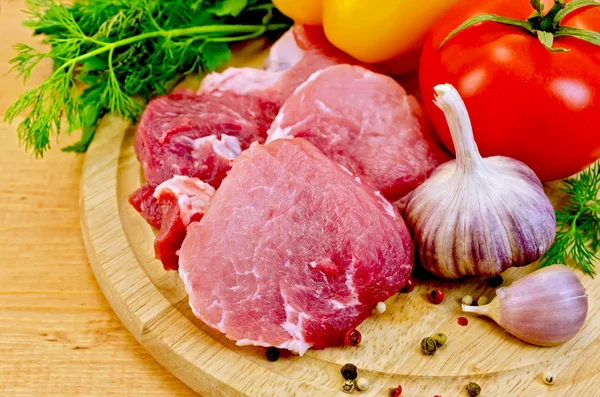 Meat slices on a wooden board with vegetables — Stock Photo, Image