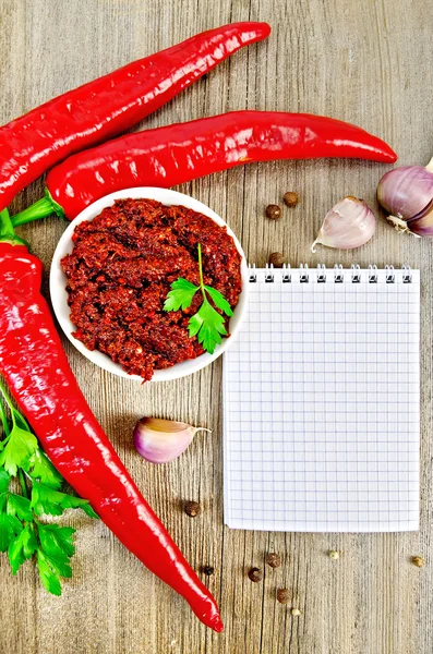 Adjika with fresh chili peppers and a notepad — Stock Photo, Image