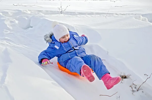 Маленькая девочка на санях скользит по снегу — стоковое фото