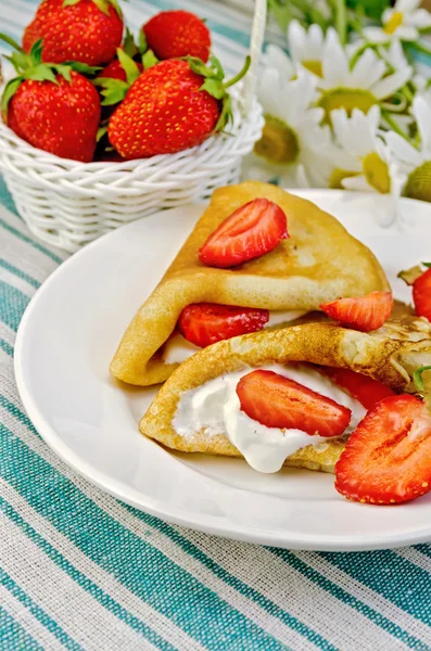 Pannenkoeken met aardbeien en mand met bessen op een servet — Stockfoto