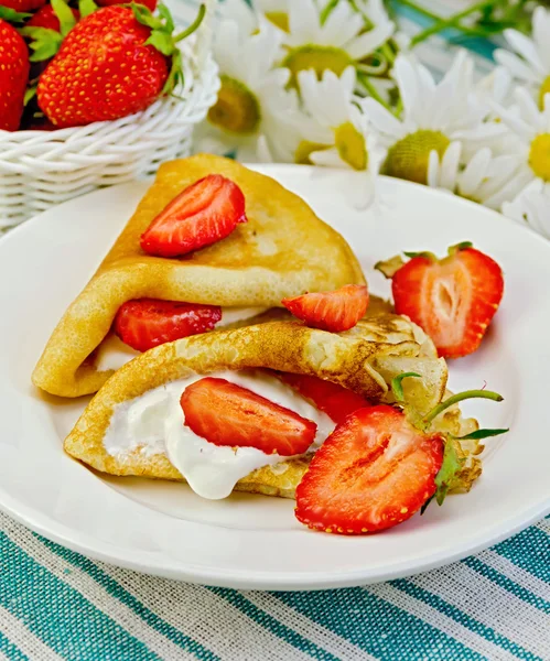 Pancakes with strawberries and daisies on a napkin — Stock Photo, Image