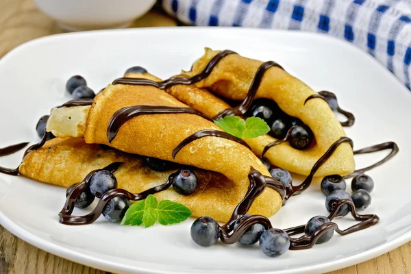 Pancakes with blueberries and chocolate syrup on the board — Stock Photo, Image