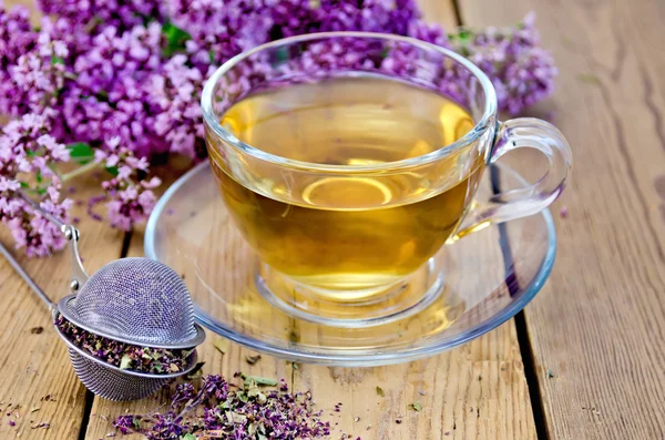 Té de hierbas de orégano con colador en una taza de vidrio —  Fotos de Stock