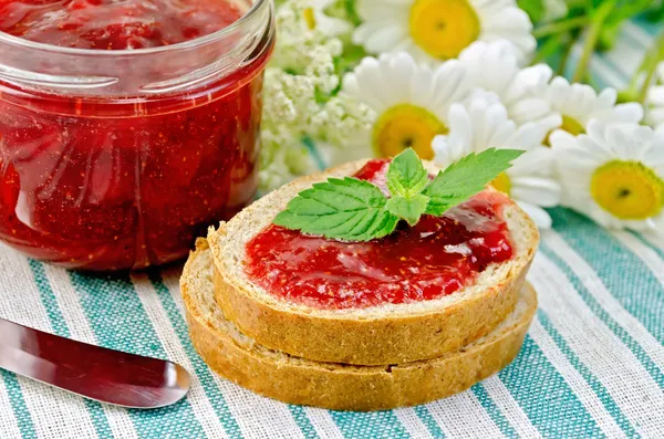 Brot mit Erdbeermarmelade und Gänseblümchen auf Serviette — Stockfoto
