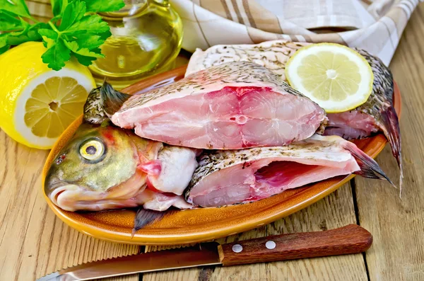 Bream raw in a clay plate with a lemon on the board — Stock Photo, Image