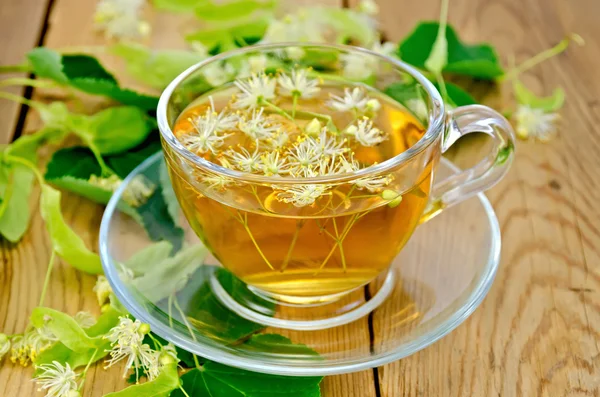 Chá de ervas de flores de tília em uma xícara na placa — Fotografia de Stock