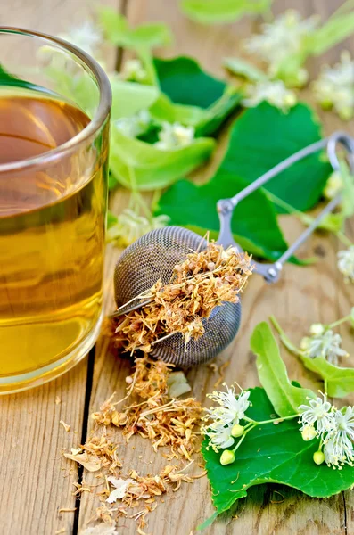 Chá de ervas de flores de tília em uma caneca com um coador no b — Fotografia de Stock