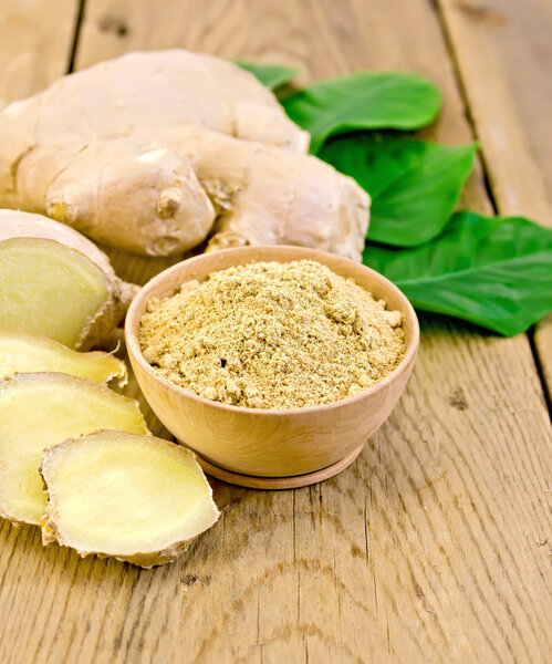Ginger powder in a bowl with the root and leaves