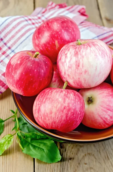 Pommes rouges dans un bol en céramique sur une planche — Photo