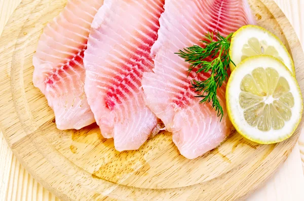 Yuvarlak bir tahtada tilapia filetosu — Stok fotoğraf