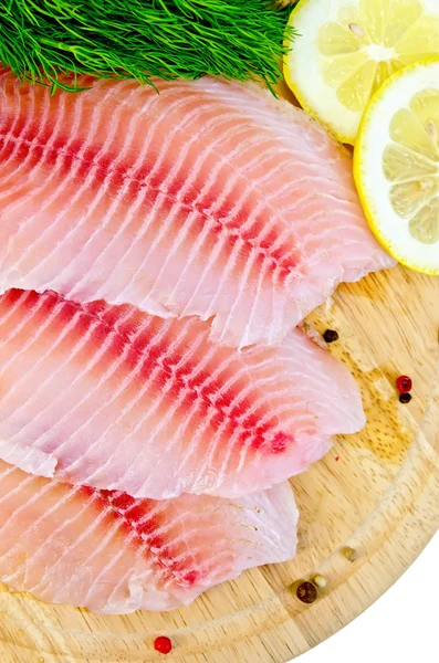 Filetes de tilapia con limón y eneldo sobre una tabla redonda —  Fotos de Stock