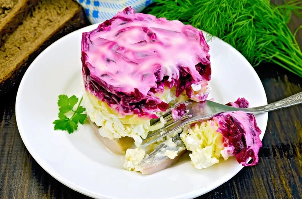 Селедка с овощами в белой тарелке с вилкой — стоковое фото