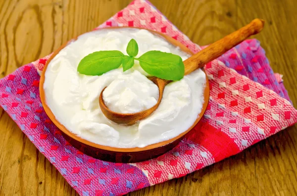 Yoghurt i en lera skål med basilika — Stockfoto