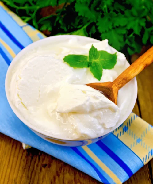 Jogurt w misce biały z drewnianą łyżką i miętą — Zdjęcie stockowe