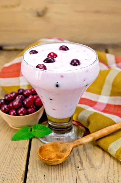 Yogurt thick with cranberries and spoon on the board — Stock Photo, Image