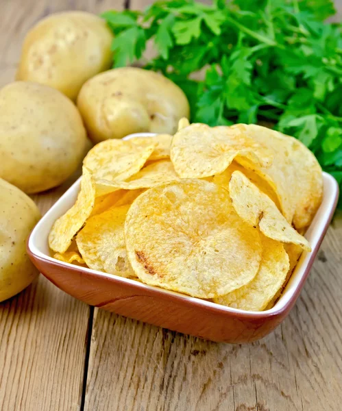 Chips in a bowl with a potato on the board — Stock Photo, Image