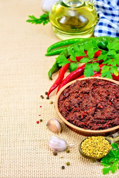 Adjika with hot pepper and a napkin on burlap — Stock Photo, Image