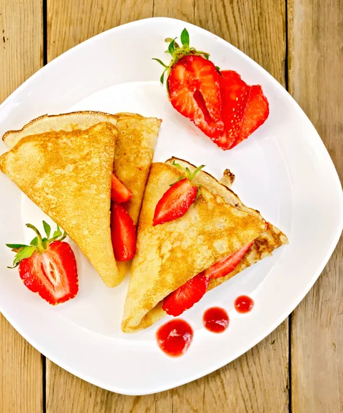 Pancakes with strawberries and jam on plate and board — Stock Photo, Image