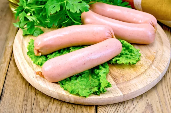 Sausages on board with parsley and napkin — Stock Photo, Image