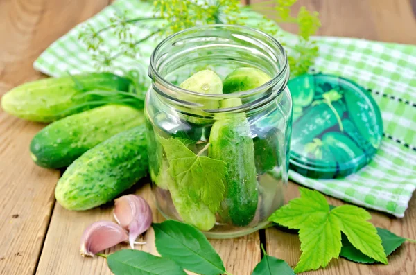 Gurkor i burk med blad och servett på bordet — Stockfoto