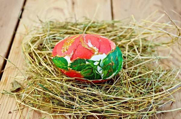Ovo de Páscoa com uma flor vermelha no feno — Fotografia de Stock