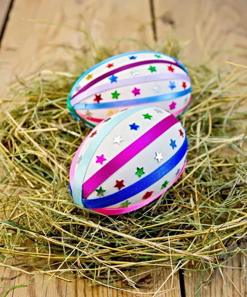 Œufs de Pâques avec rubans et paillettes dans le foin — Photo