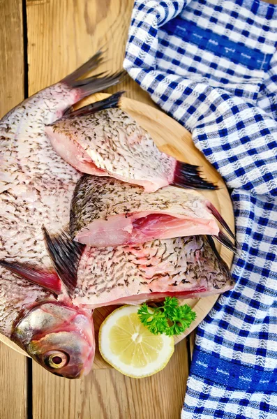 Bream mentah di papan dengan pisau dan serbet — Stok Foto