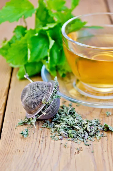 Herbal tea from melissa in cup with strainer on board — Stock Photo, Image