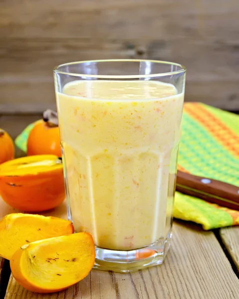 Milkshake with persimmons in glass on board — Stock Photo, Image