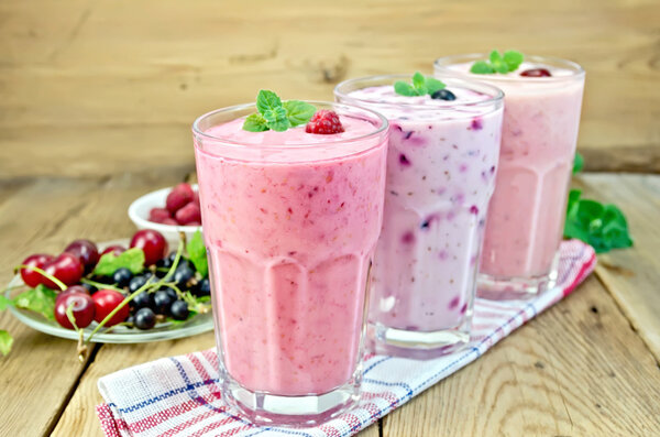 Milkshakes with berries in glass on board